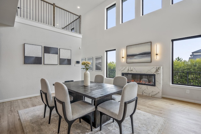 dining space with plenty of natural light, baseboards, a premium fireplace, and light wood-type flooring