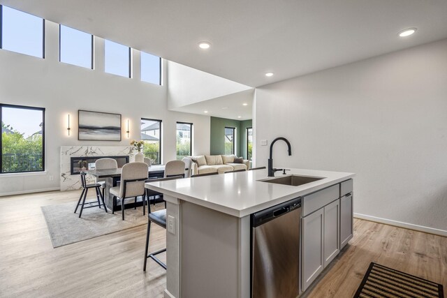 kitchen with open floor plan, an island with sink, gray cabinets, a sink, and dishwasher