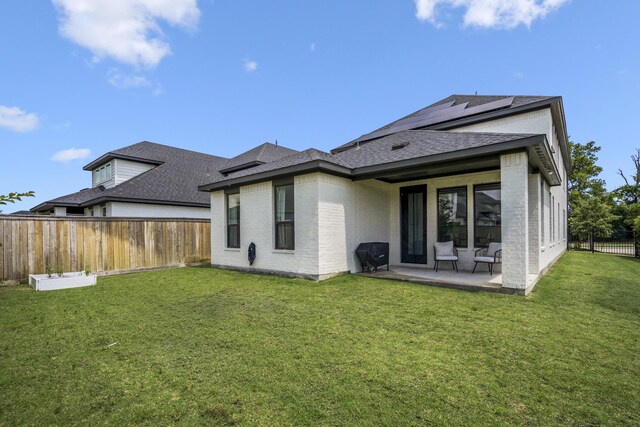 back of house with a shingled roof, brick siding, a fenced backyard, a patio area, and a yard