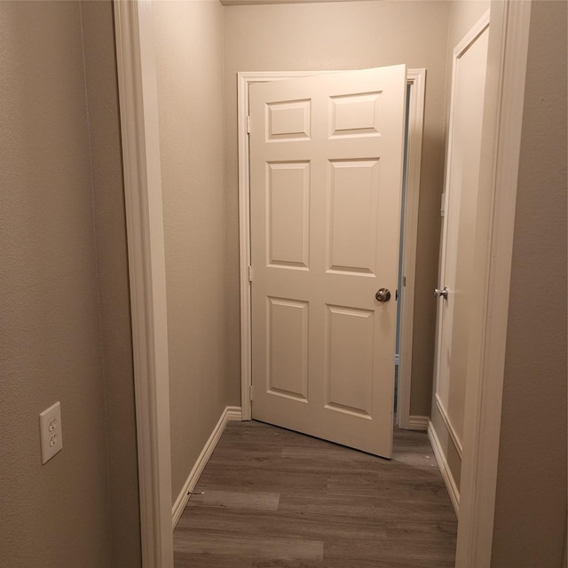 corridor featuring baseboards and dark wood finished floors