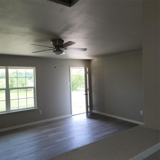 spare room with baseboards, ceiling fan, dark wood finished floors, and a textured ceiling