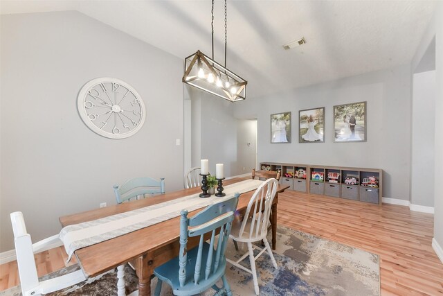 dining area with visible vents, wood finished floors, and lofted ceiling