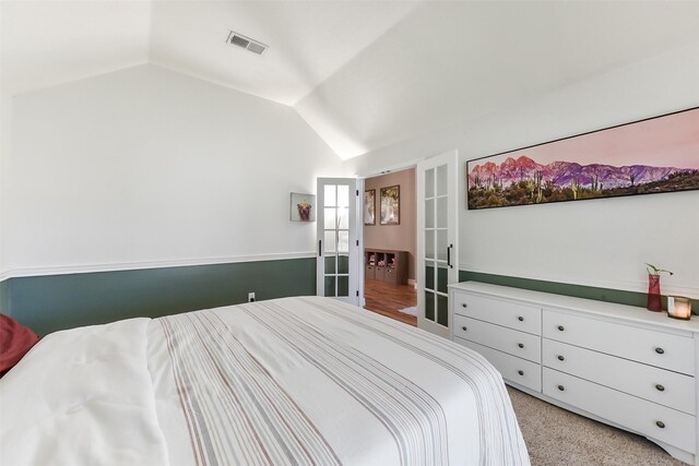 bedroom featuring light carpet, lofted ceiling, and visible vents