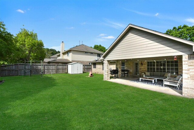 back of house featuring a patio area, a fenced backyard, a shed, an outdoor living space with a fire pit, and a yard