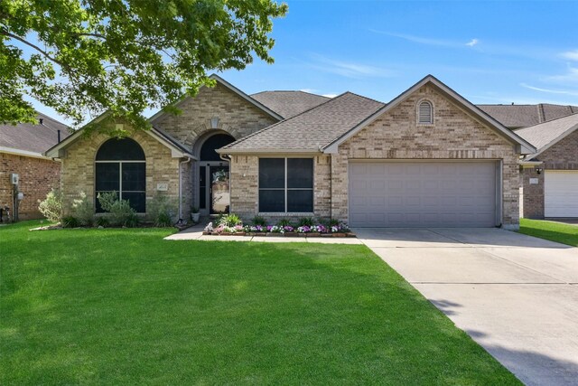 view of front of home with brick siding, a garage, a front lawn, and driveway