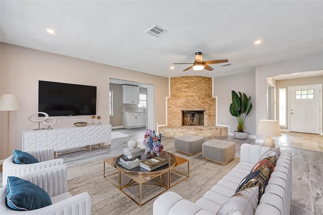 living room with a ceiling fan, visible vents, a healthy amount of sunlight, and light wood-style floors