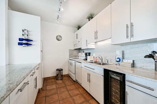kitchen featuring white cabinets, white appliances, rail lighting, tasteful backsplash, and wine cooler