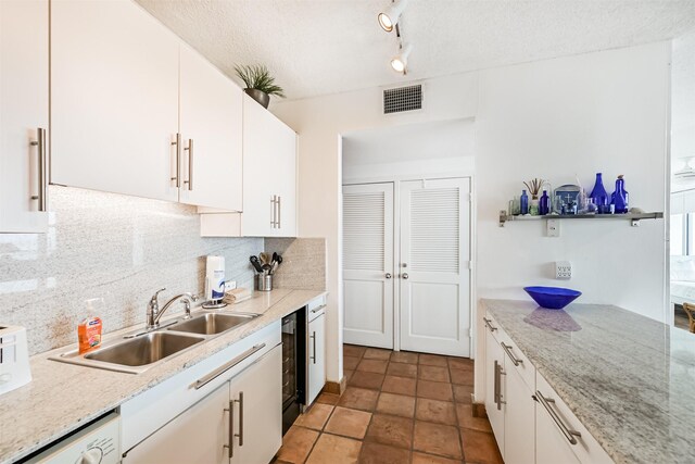 kitchen featuring backsplash, wine cooler, a sink, dishwashing machine, and white cabinetry