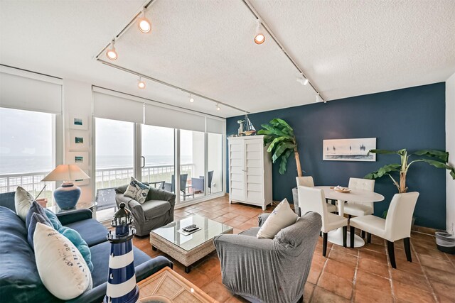 living room featuring track lighting, a water view, and a textured ceiling