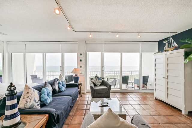 tiled living area featuring a textured ceiling, track lighting, and plenty of natural light