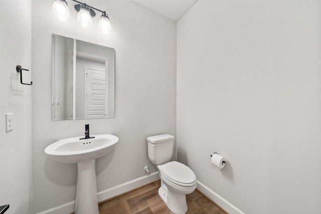 bathroom with baseboards, wood finished floors, and toilet