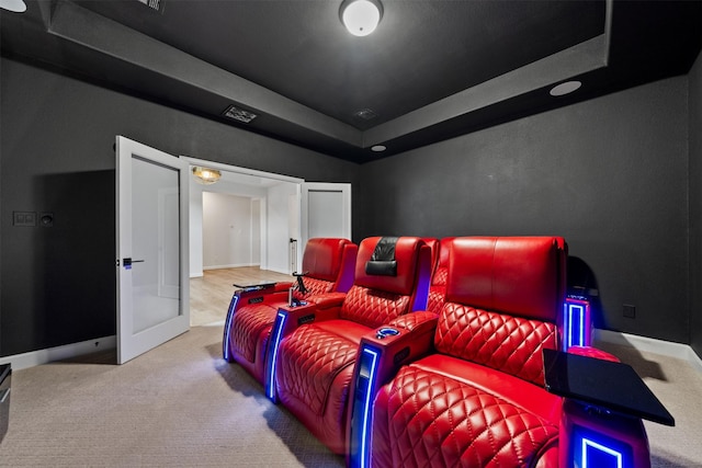 carpeted cinema with baseboards and a raised ceiling