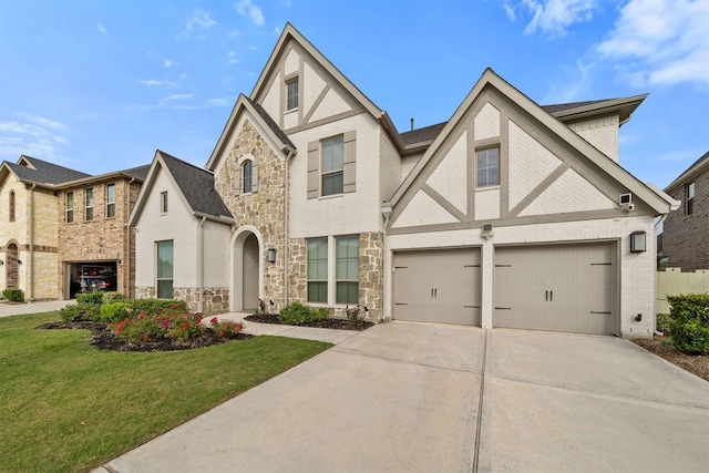 english style home featuring concrete driveway, a front yard, and stone siding