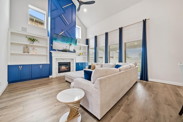 living room with baseboards, light wood-style flooring, a healthy amount of sunlight, and high vaulted ceiling