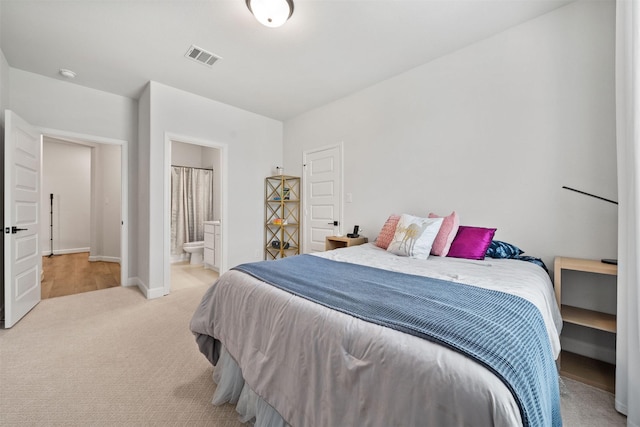 bedroom with baseboards, light carpet, connected bathroom, and visible vents