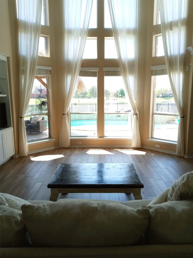 living room featuring a high ceiling, a healthy amount of sunlight, and hardwood / wood-style flooring