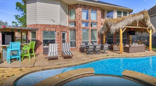 view of swimming pool featuring fence, a patio, a pool with connected hot tub, and an outdoor living space