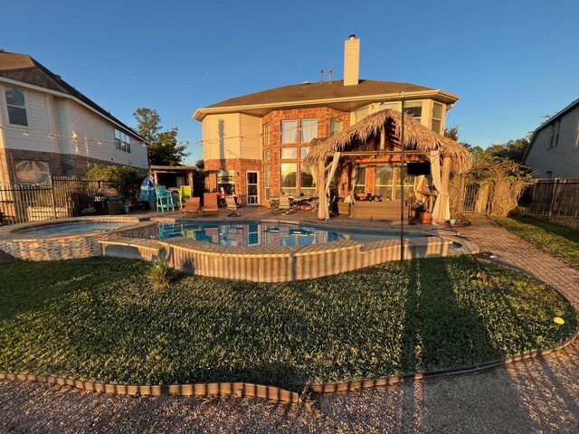 rear view of house with a patio, a fenced backyard, a chimney, an outdoor living space, and a pool with connected hot tub