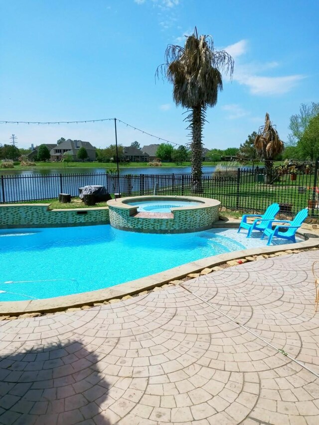 view of swimming pool featuring a water view, a pool with connected hot tub, a fenced backyard, and a patio area