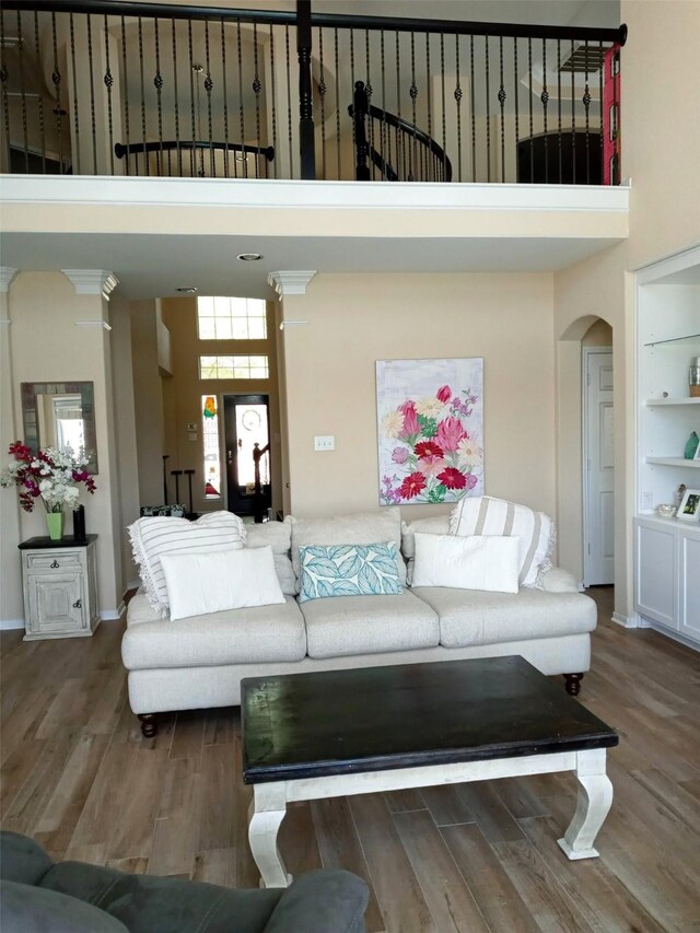 living room featuring wood finished floors, arched walkways, and a high ceiling
