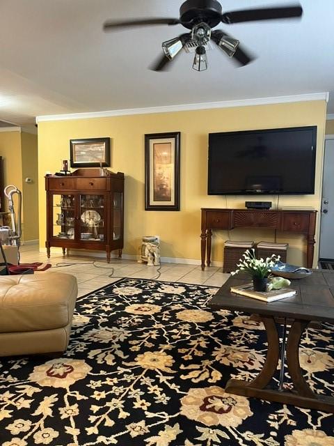 living room with crown molding, baseboards, ceiling fan, and tile patterned floors