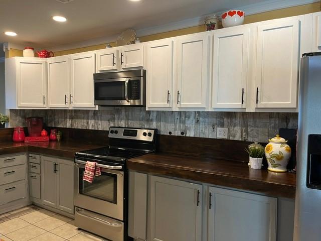 kitchen featuring dark countertops, appliances with stainless steel finishes, light tile patterned floors, and white cabinetry