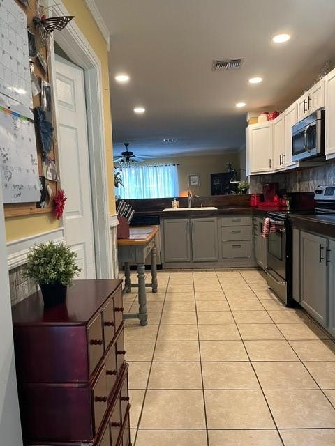 kitchen with visible vents, dark countertops, gray cabinets, light tile patterned floors, and stainless steel appliances