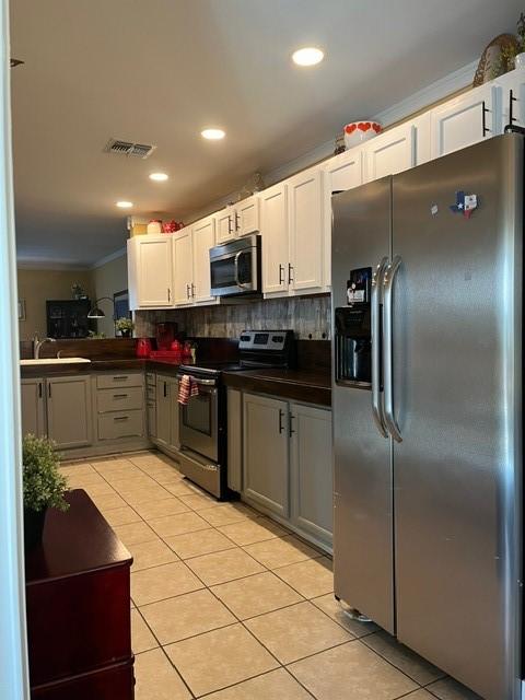 kitchen with stainless steel appliances, dark countertops, visible vents, and light tile patterned floors