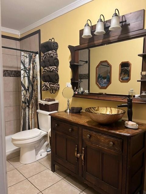 bathroom with toilet, ornamental molding, tiled shower, and tile patterned flooring