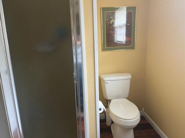 bathroom featuring baseboards, a stall shower, and toilet