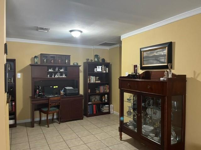 office area with light tile patterned flooring, baseboards, visible vents, and ornamental molding