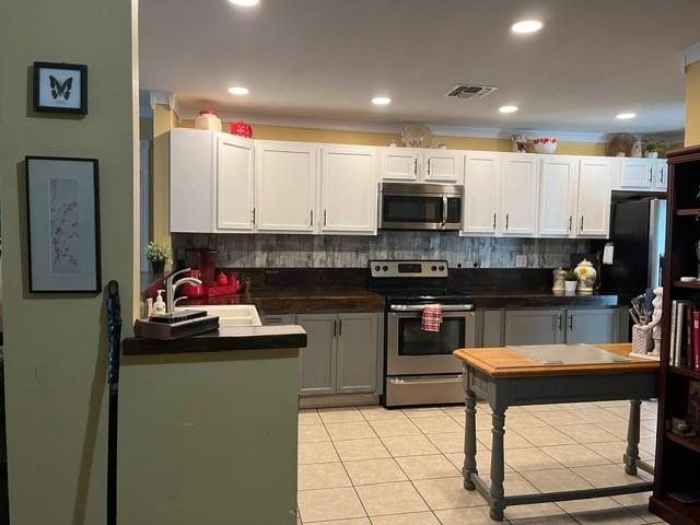kitchen featuring dark countertops, a sink, stainless steel appliances, decorative backsplash, and visible vents