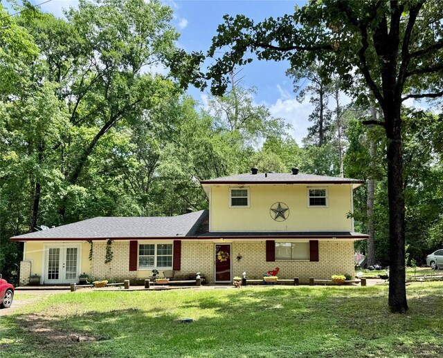 view of front of property featuring french doors, a front lawn, and brick siding