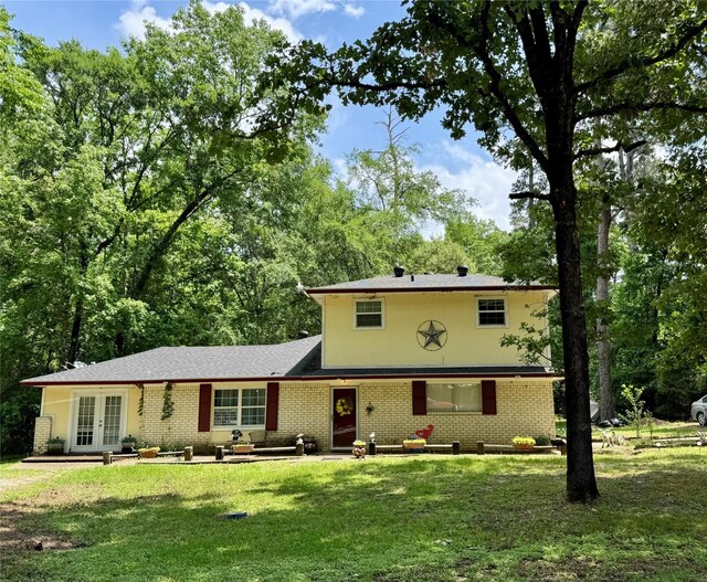 view of front facade featuring brick siding, french doors, and a front yard