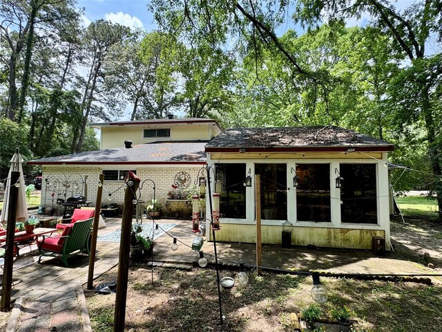 rear view of house featuring brick siding and a patio
