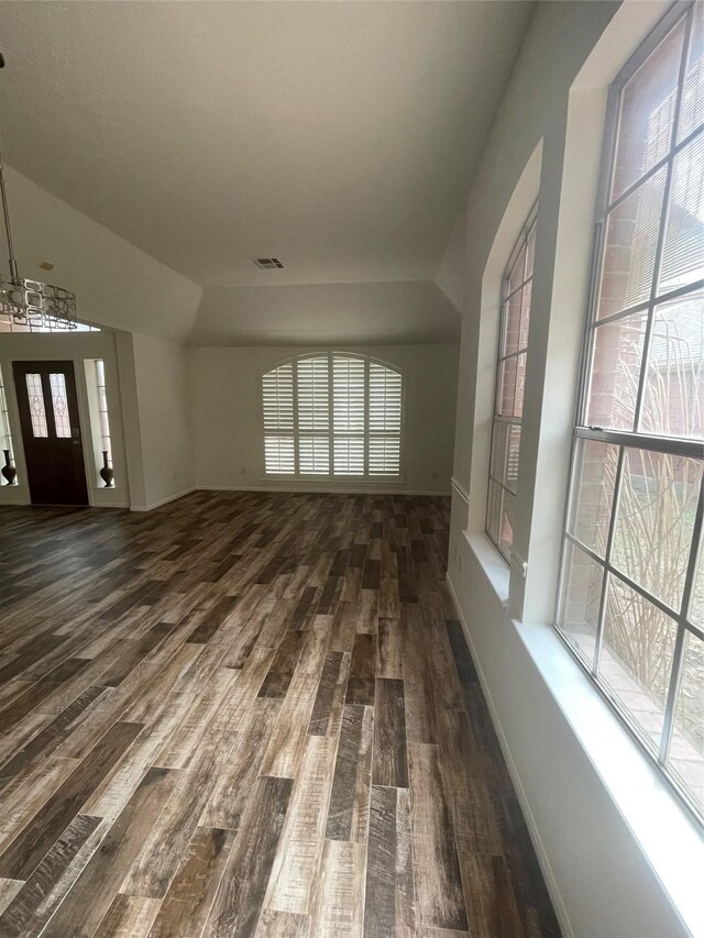 unfurnished living room featuring visible vents, wood finished floors, and a notable chandelier