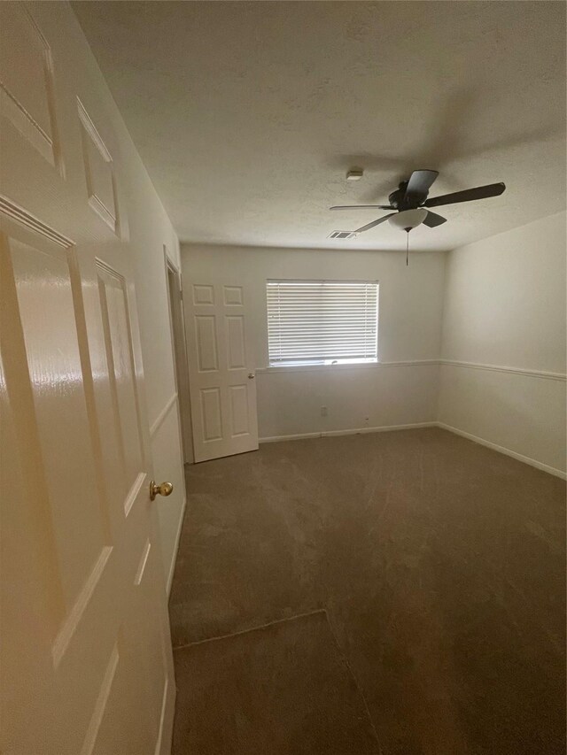 unfurnished room with dark carpet, a ceiling fan, and baseboards