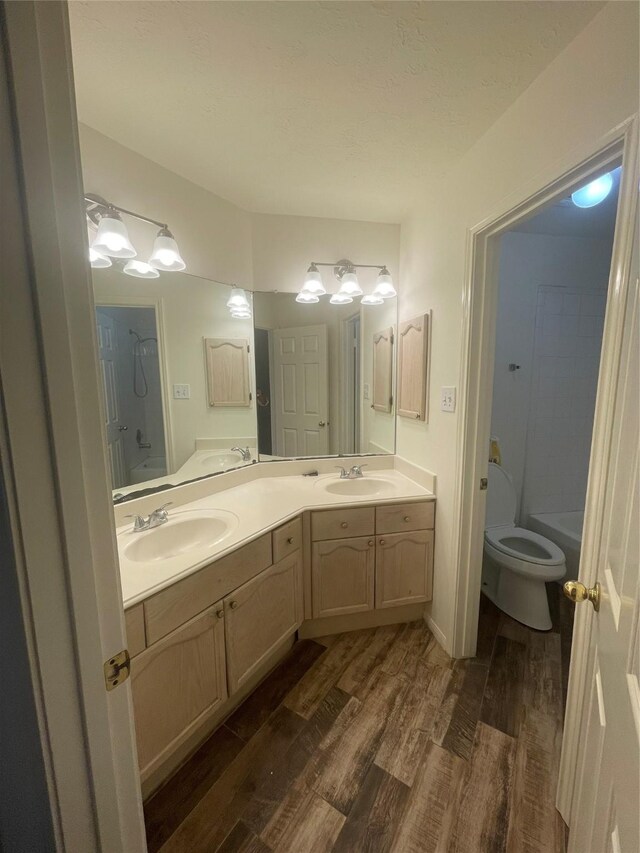 bathroom featuring a sink, double vanity, toilet, and wood finished floors