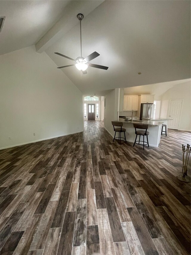 unfurnished living room with dark wood-style flooring, a ceiling fan, visible vents, and vaulted ceiling with beams