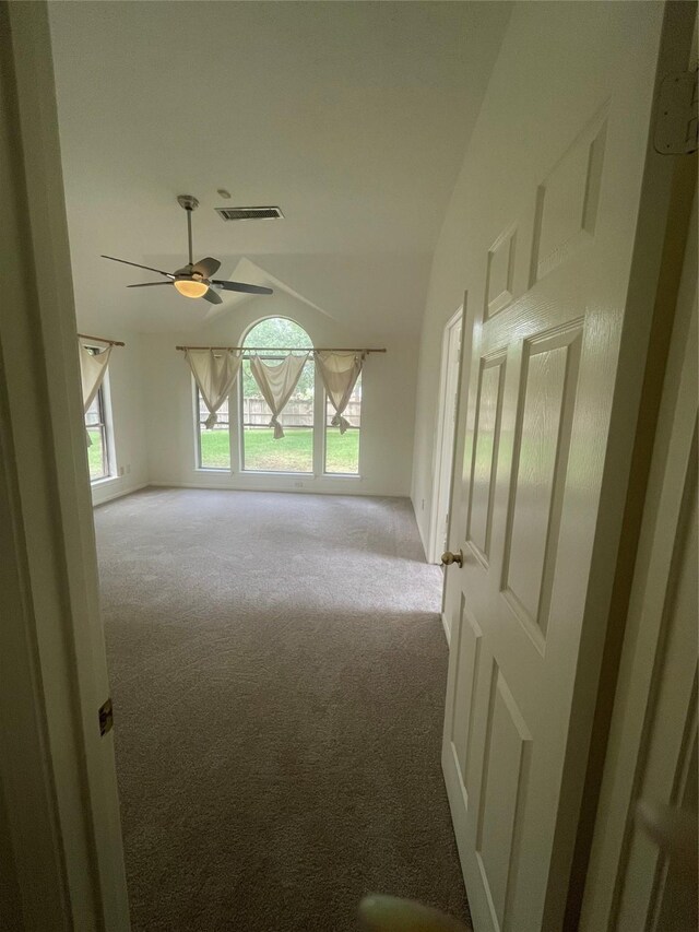 unfurnished room with visible vents, carpet flooring, a ceiling fan, and vaulted ceiling