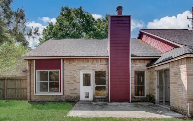 back of house featuring fence, a shingled roof, a chimney, a patio area, and a yard