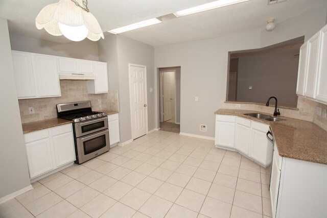kitchen with a sink, under cabinet range hood, backsplash, and range with two ovens