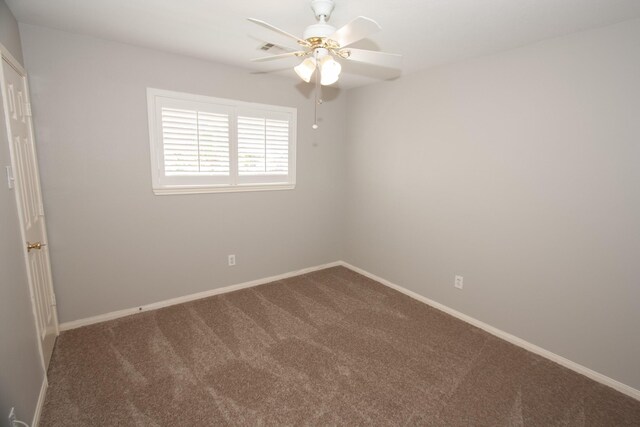 unfurnished room with dark carpet, baseboards, ceiling fan, and visible vents