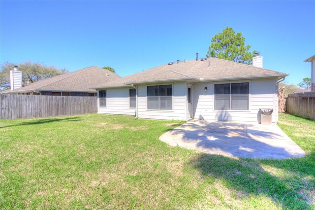 rear view of property featuring a patio, a fenced backyard, a yard, and a chimney
