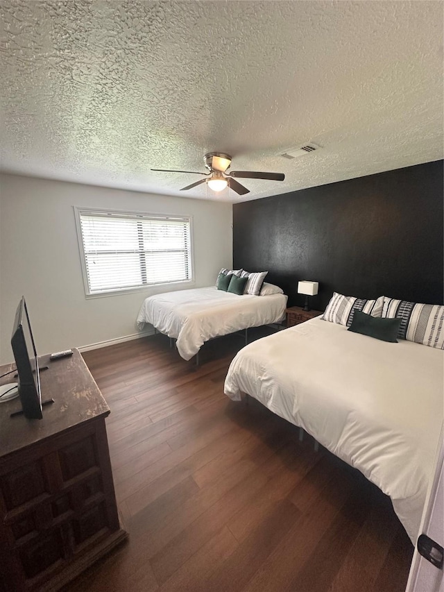 bedroom featuring visible vents, a ceiling fan, a textured ceiling, and dark wood-style floors