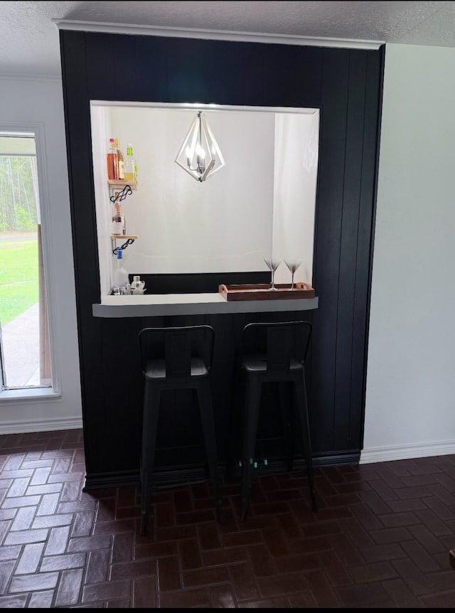 bar featuring baseboards, crown molding, and brick floor