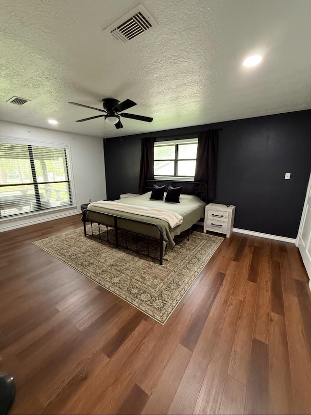 bedroom featuring a textured ceiling, ceiling fan, wood finished floors, and visible vents