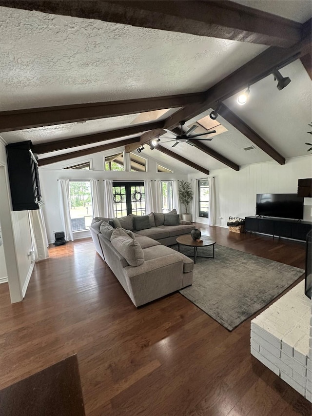 living area with ceiling fan, lofted ceiling with beams, a textured ceiling, dark wood-type flooring, and visible vents