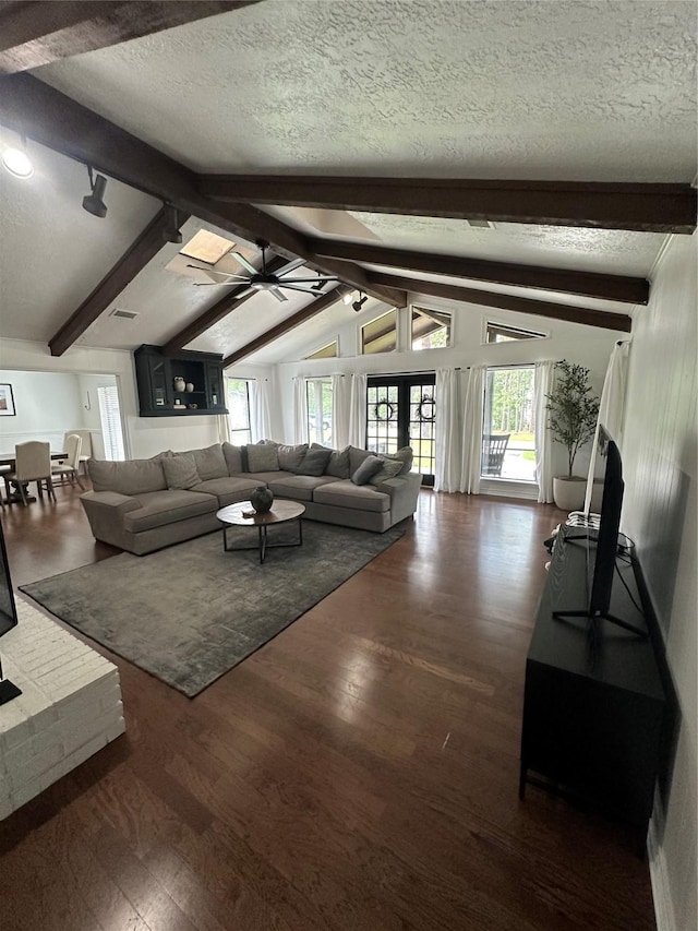 living area featuring plenty of natural light, lofted ceiling with beams, a textured ceiling, and wood finished floors