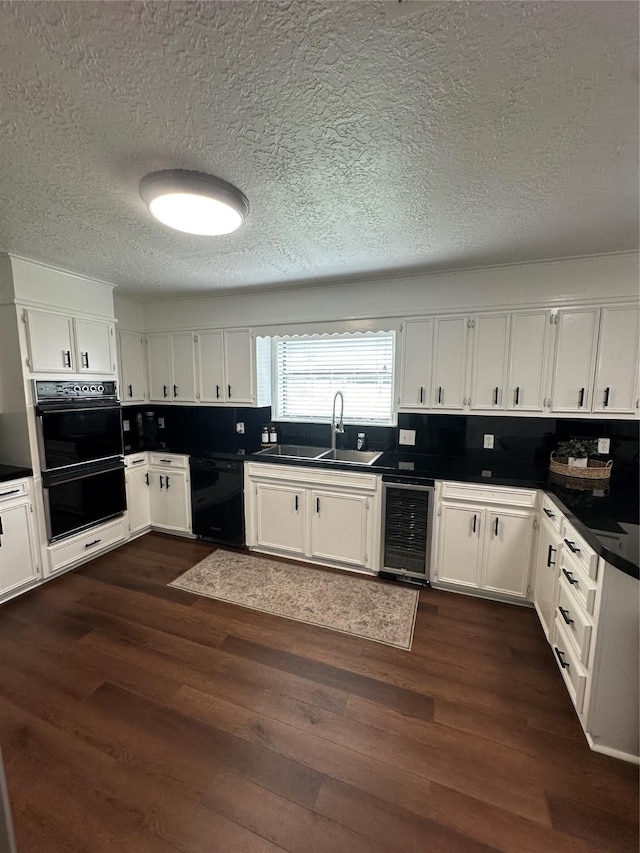 kitchen featuring wine cooler, dark countertops, white cabinetry, a sink, and black appliances